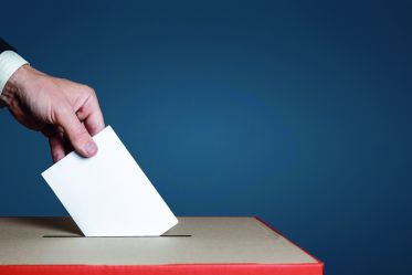 Voter hand puts the ballot into the ballot box. The concept of democracy and elections